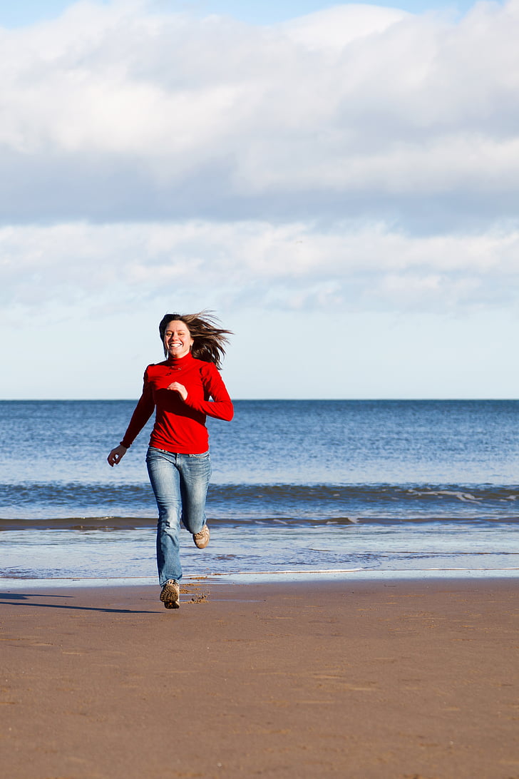 woman wearing red long-sleeved shirt running on beach
