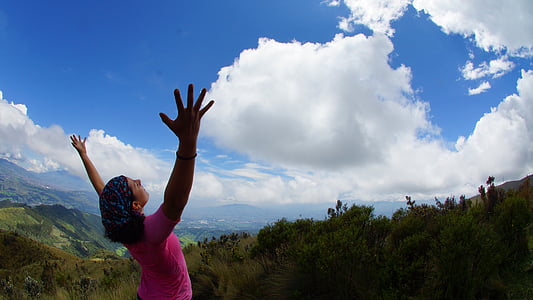 woman raising her hand at the mountain top