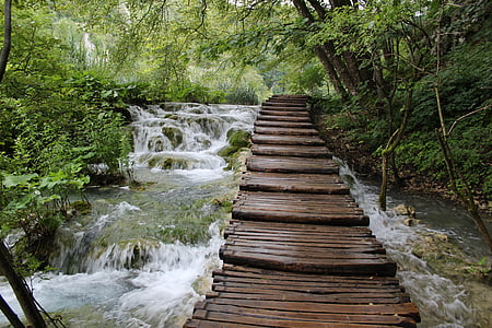 time-lapse photography of brown wooden bridge above waterfalls