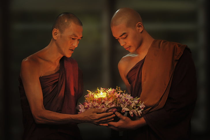 two monks carrying flowers with candle