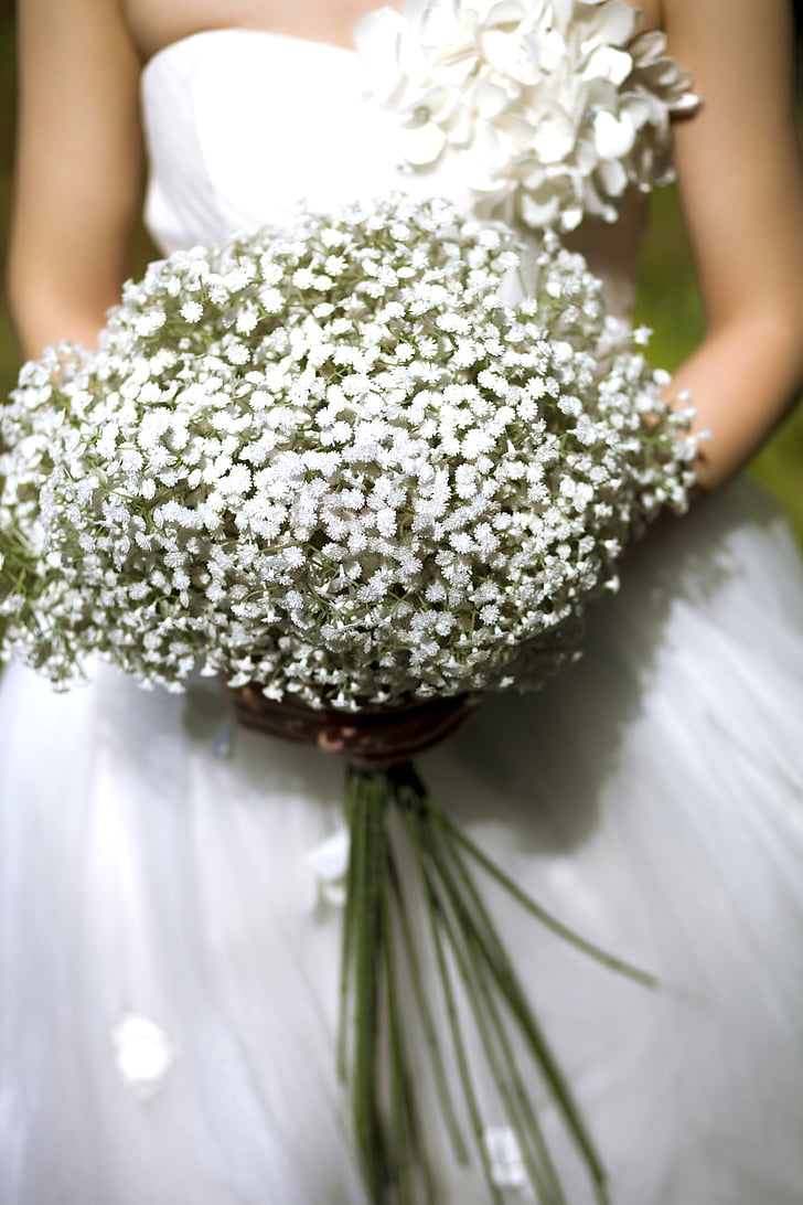 photo of woman wearing white wedding dress holding white petaled flowers bouquet