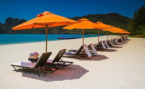 row lounger chairs and parasols on shore at daytime