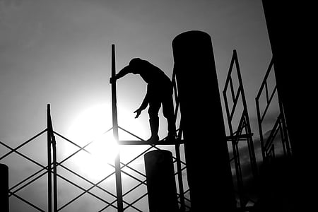 silhouette photography of man standing on scaffold