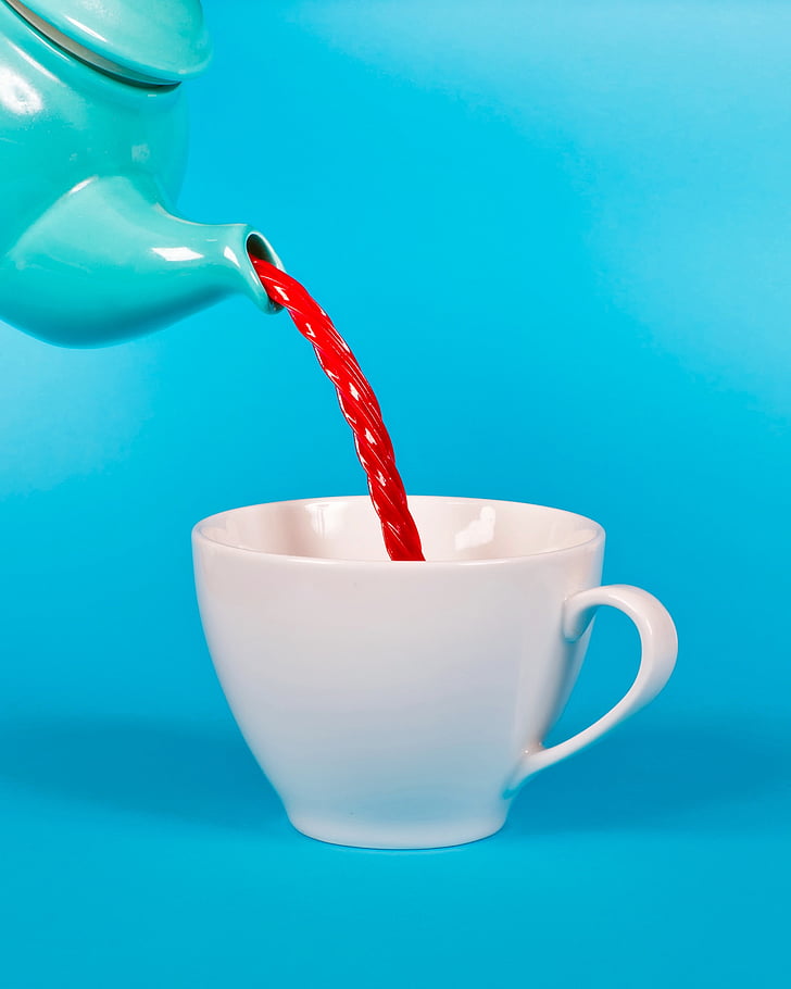 teapot pouring red beverage on mug