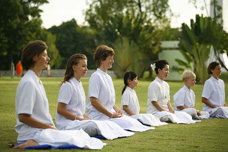 people sitting on grass while meditating