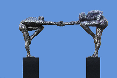 two human holding hand statue under clear sky