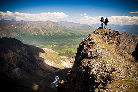 two people standing on mountain peak during daytime