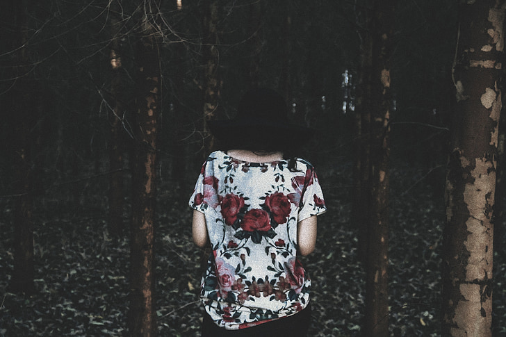 person wearing white and red floral boat-neck blouse in the middle of forest