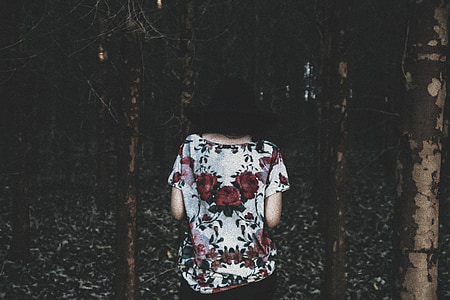 person wearing white and red floral boat-neck blouse in the middle of forest