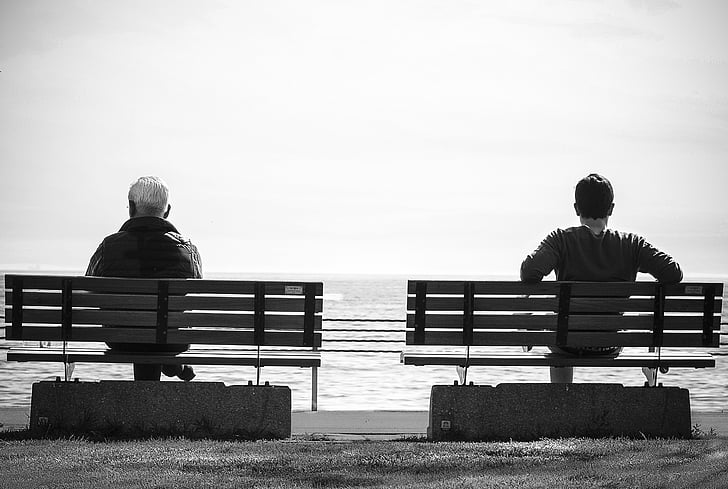 grayscale photography of men sitting on bench