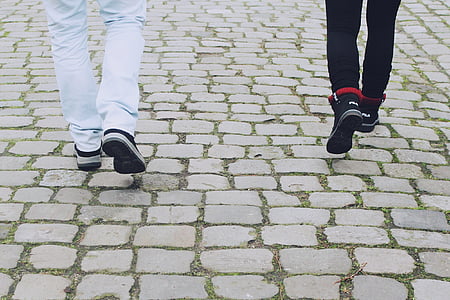 two person wearing white and black pants and sneakers walking on pavement