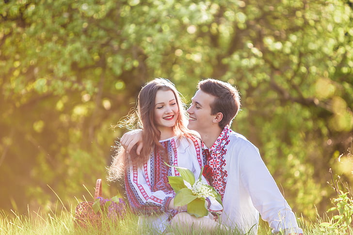 woman and man sitting on green grass field during daytime