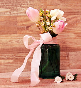 white flowers in green glass vase with pink ribbon