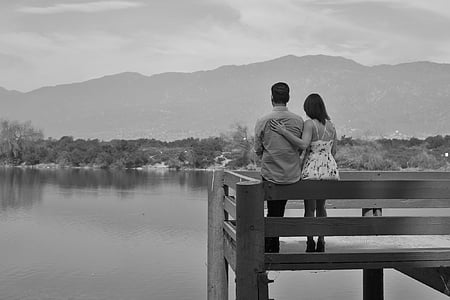 couple sitting on fence near body of water
