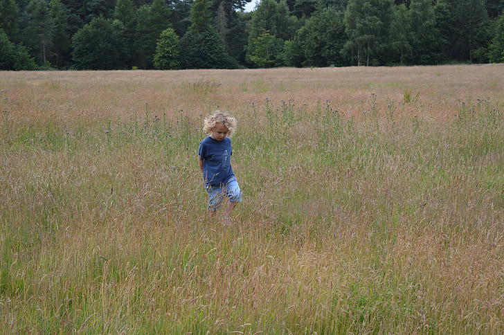 toddler standing in the middle of grass