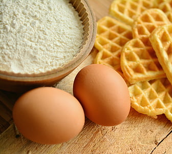 two eggs, white powder on brown bowl, and waffle