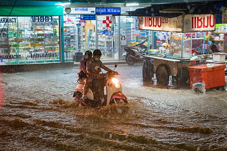 two people on motor scooter in middle of flood