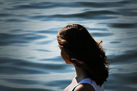 woman wearing white tank top facing ocean