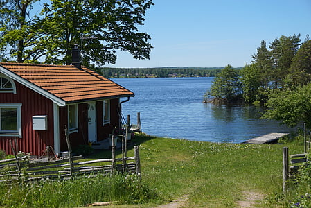 red wooden house beside body of water during daytime