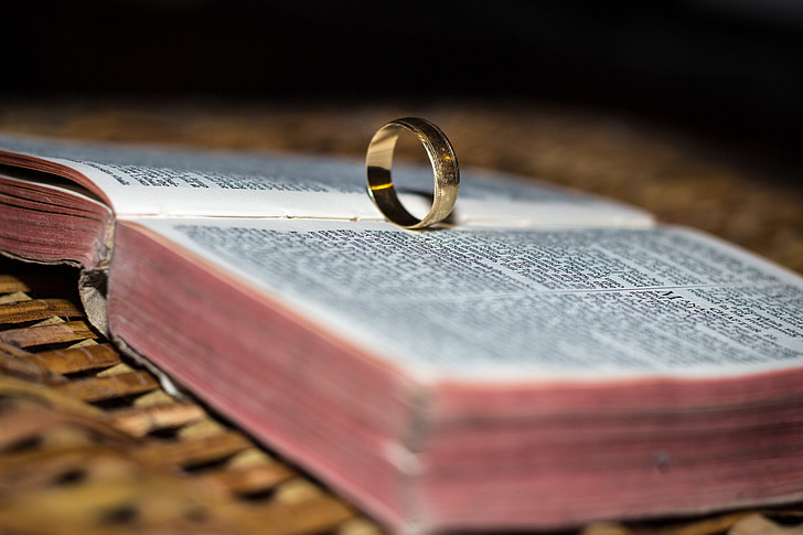 gold-colored ring on opened Bible selective focus photo