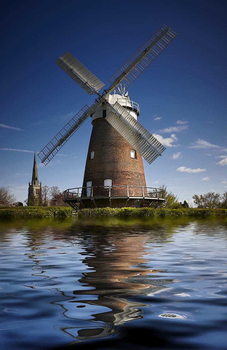brown windmill beside the body of water