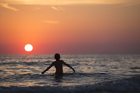 boy on body of water during sun set