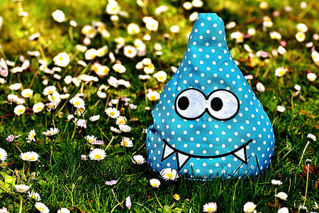 blue and white monster plush toy on daisy flowers at daytime