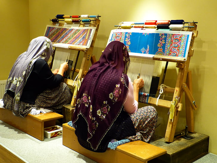 two woman wearing shawls weaving