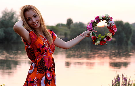 woman in red dress holding floral headband during daytime