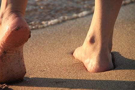 shallow focus photography person's foot standing on beach sand during daytime