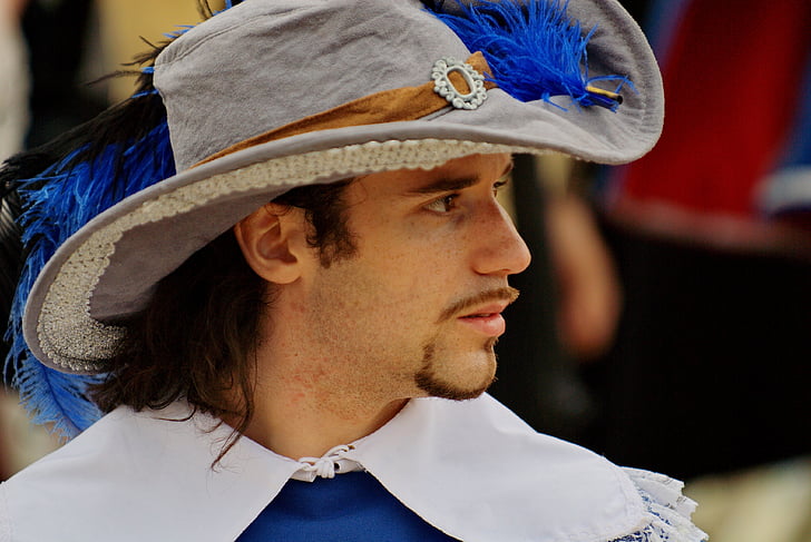 man wearing gray and blue feather hat