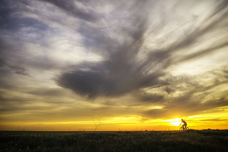 silhouette of person biking during sunset l