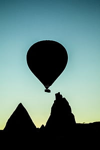silhouette of hot air balloon flying distance with mountains at blue hour