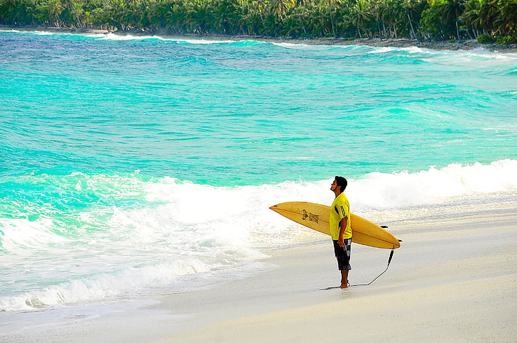man holding yellow surfboard on beach