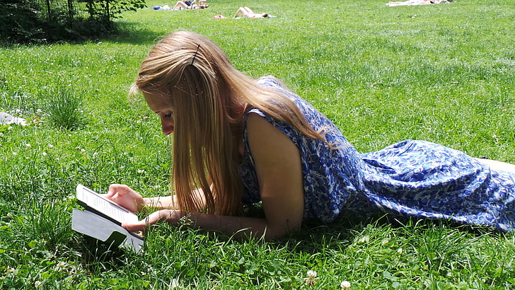 woman in blue floral sleeveless dress lying on grass