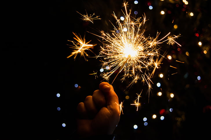 person holding sparkler with background of boke lights