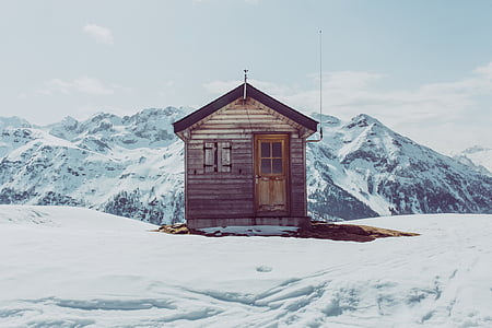 brown wooden house on snow field