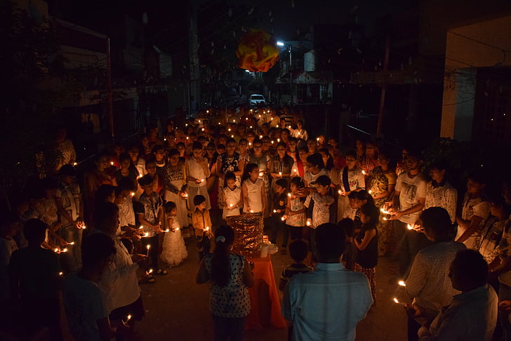 group of people holding candles while huddling