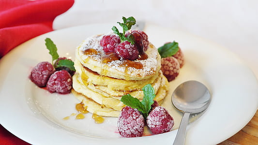 pancakes served on white ceramic plate with raspberries