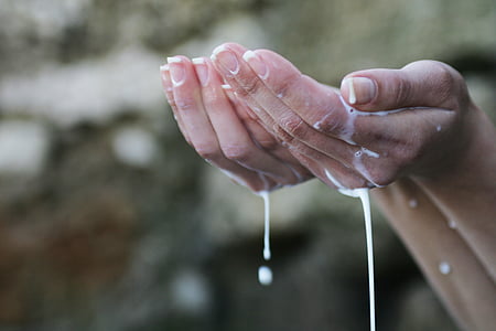 selective focus photography of person's hand holding white liquid