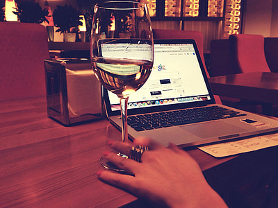 glass of champagne beside MacBook Pro on brown wooden desk