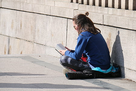woman wearing blue denim jacket and black pants reading book