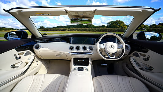 grey and black Mercedes-Benz vehicle interior overlooking green grass field and trees under cloudy sky during daytime