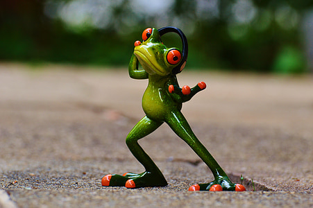 selective focus photography of red and green frog wearing headset figurine on brown surface