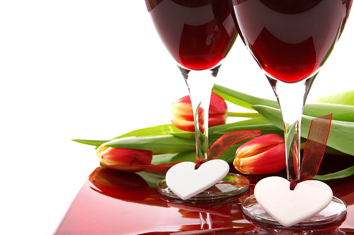two clear wine glasses near red tulip flowers
