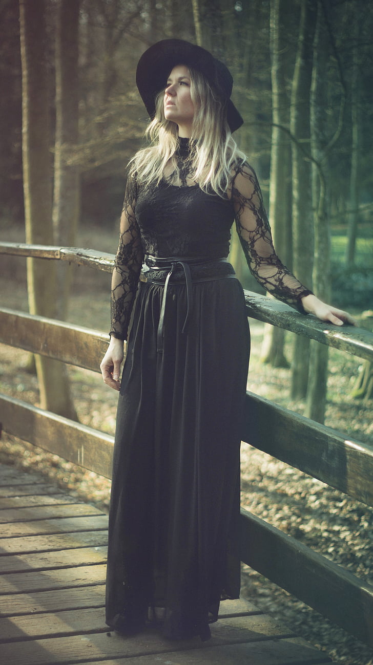 woman wearing black lace long-sleeved long dress near brown wooden fence in forest