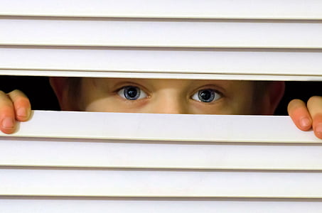 boy peeking from white window blinds