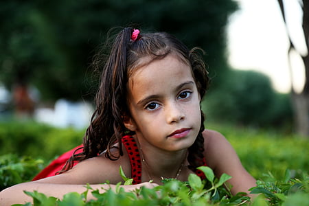 shallow focus photography of girl on grass field during daytime