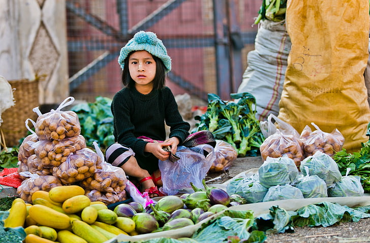 girl sitting in front of vegetables
