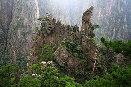 brown rock formation with trees under a mountain at daytime